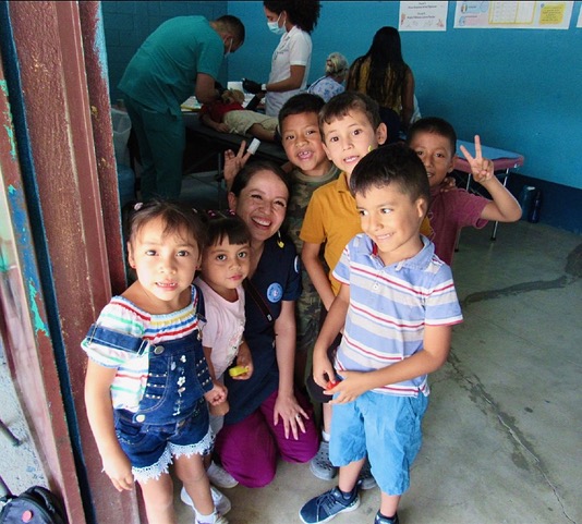 students with a volunteer man next to woman in front of bulleting board